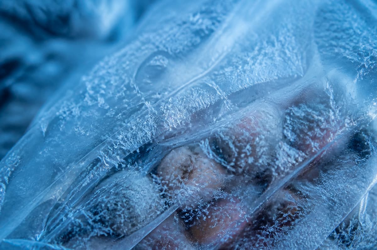 Gros plan sur un emballage alimentaire surgelé recouvert de cristaux de glace nets et brillants.