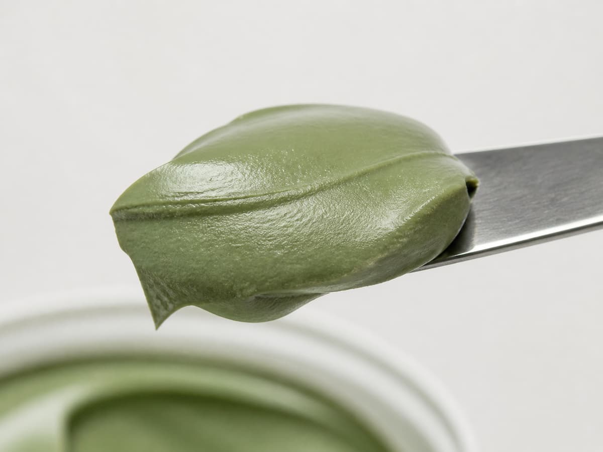 Spatule soulevant une pâte d'argile verte lisse et homogène sans grumeaux, montrant une consistance souple et stable.